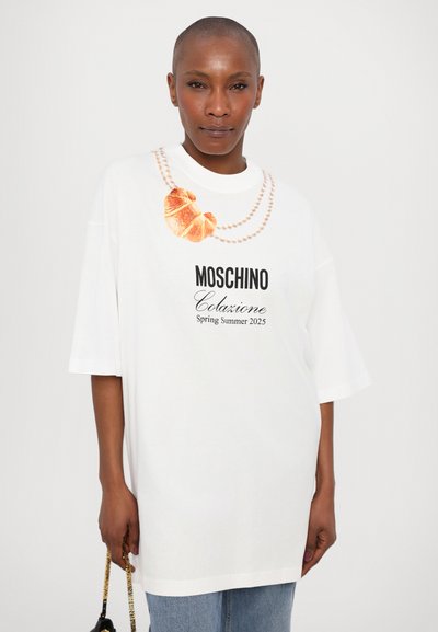 White oversized t-shirt featuring a croissant graphic, pearl necklace design, and "Moschino Colazione Spring Summer 2025" text.