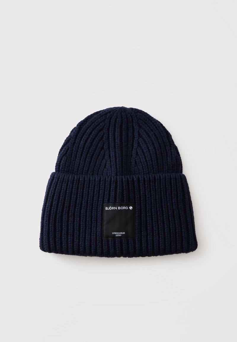 Bonnet en tricot côtelé bleu marine avec revers et étiquette rectangulaire noire portant la mention "BJÖRN BORG STOCKHOLM 1956" sur le devant.