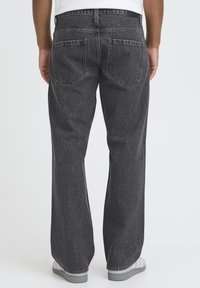 Jean en denim noir à coupe décontractée, avec deux poches arrière et une texture légèrement délavée. Conçu dans un style classique à cinq poches.