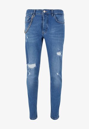 Jean skinny bleu en denim avec des déchirures usées aux genoux, doté d'un accent en chaîne métallique attaché à la taille.