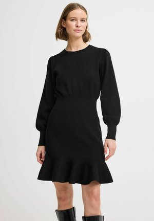 Schwarzes gestricktes Kleid mit langen, gepufften Ärmeln, taillierter Taille und einem ausgestellten, rüschierten Saum; glatte Textur und klassischer runder Ausschnitt.