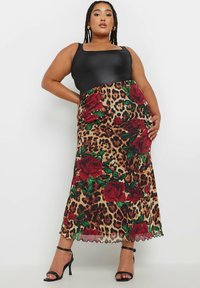 Top negro sin mangas combinado con una falda de estampado de leopardo adornada con rosas rojas, dobladillo festoneado y una silueta fluida.