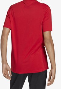 Röd bomullströja med korta ärmar, rundad hals och en slät textur; visad från baksidan med enkel design och utan ytterligare detaljer.