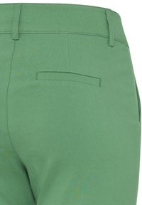 Pantalon vert à texture lisse, avec une poche arrière et des détails de couture simples. La coupe est ajustée avec une jambe droite.