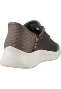 Zapatilla deportiva gris con un exterior texturizado, paneles de malla para transpirabilidad y una suela acolchada blanca. Presenta una etiqueta de logo en el lateral.