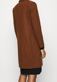 Brun uldblandingsfrakke med en skræddersyet design, der har en høj krave, lange ærmer og en lige pasform, der strækker sig til midt på låret.