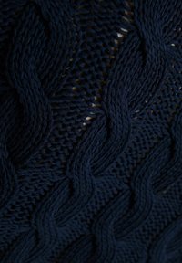 Granatowa dzianina z teksturowanymi, przeplatającymi się wzorami fal, zawierająca otwarte sploty i gładką przędzę.