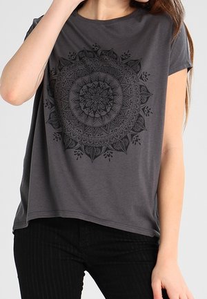 Šedé tričko s krátkými rukávy, které na středu zdobí černý mandala design. Měkká látka s volným střihem a kulatým výstřihem.