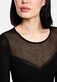 Black ribbed top featuring a sheer, textured upper section with a V-shaped design, round neckline, and solid black lower part.