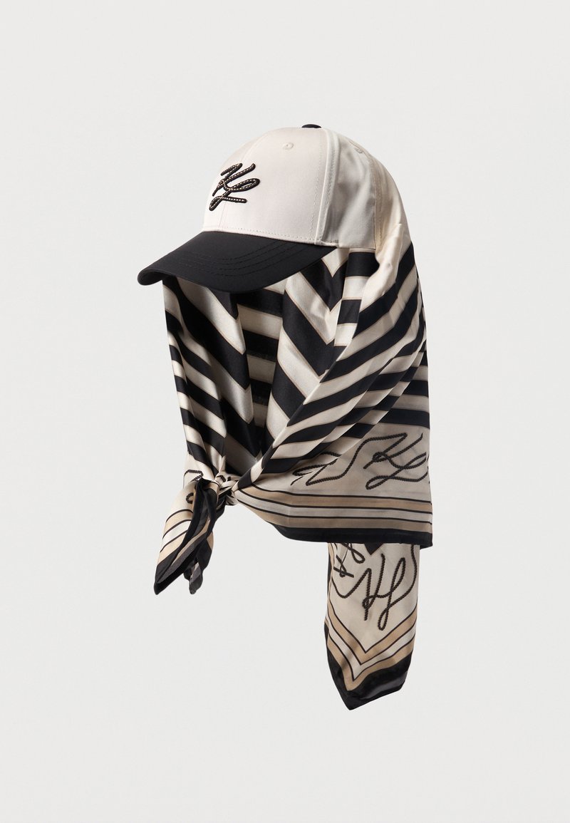 Λευκό και μαύρο μπέιζμπολ καπέλο με μαύρο κεντημένο λογότυπο, συνδυασμένο με μαύρο και λευκό ριγέ κασκόλ με κόμπο, που διαθέτει λεπτομέρειες σε γραφή.