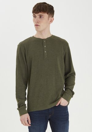 Langærmet olivengrøn henley-shirt lavet af tekstureret stof, med en rund hals, tre knapper ved kraven og tætsiddende manchetter.