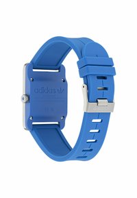 Montre en résine bleue avec un cadran carré et des éléments en métal argenté. Elle dispose d'un bracelet flexible avec des découpes pour un ajustement de taille.