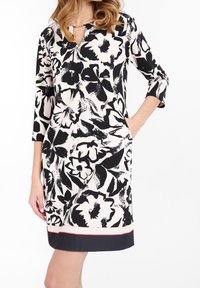 Robe à imprimé floral en noir et blanc, avec un décolleté en V, des manches trois-quart, des poches latérales et un ourlet contrastant bleu marine avec un accent rouge.