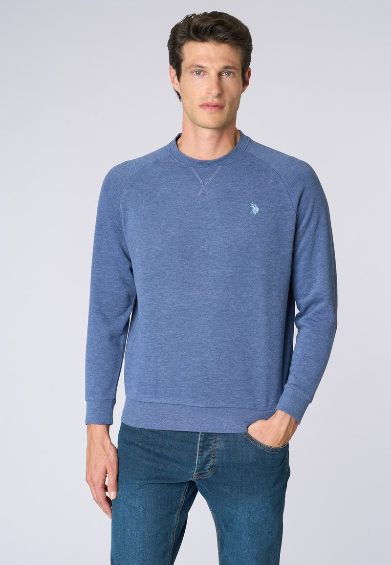 Felpa blu realizzata in un tessuto testurizzato, con colletto tondo e polsini a coste. Un piccolo logo è visibile sul lato sinistro del petto.