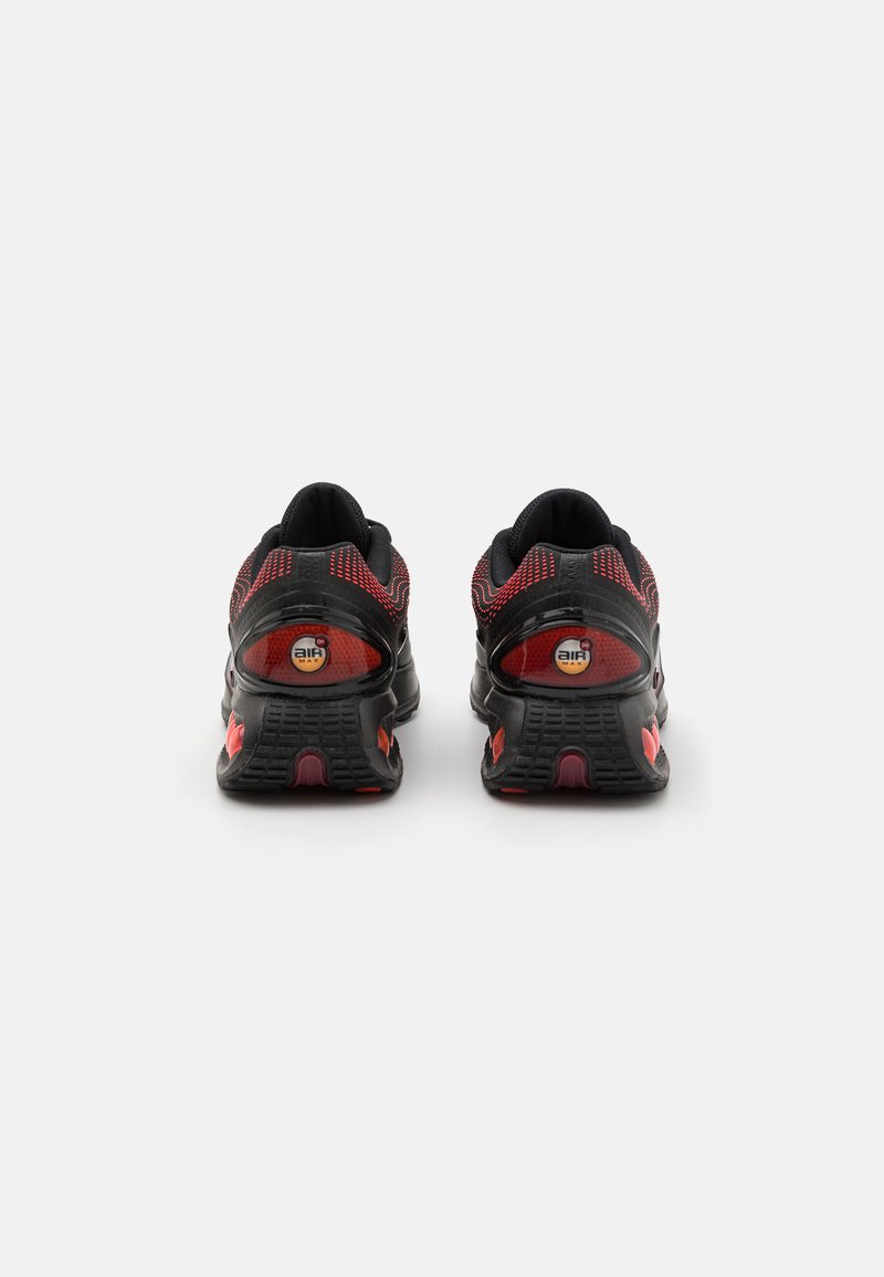 Baskets de sport noires et rouges avec tige en maille, semelle texturée et amorti de talon proéminent. Présente des accents de logo et un design respirant.
