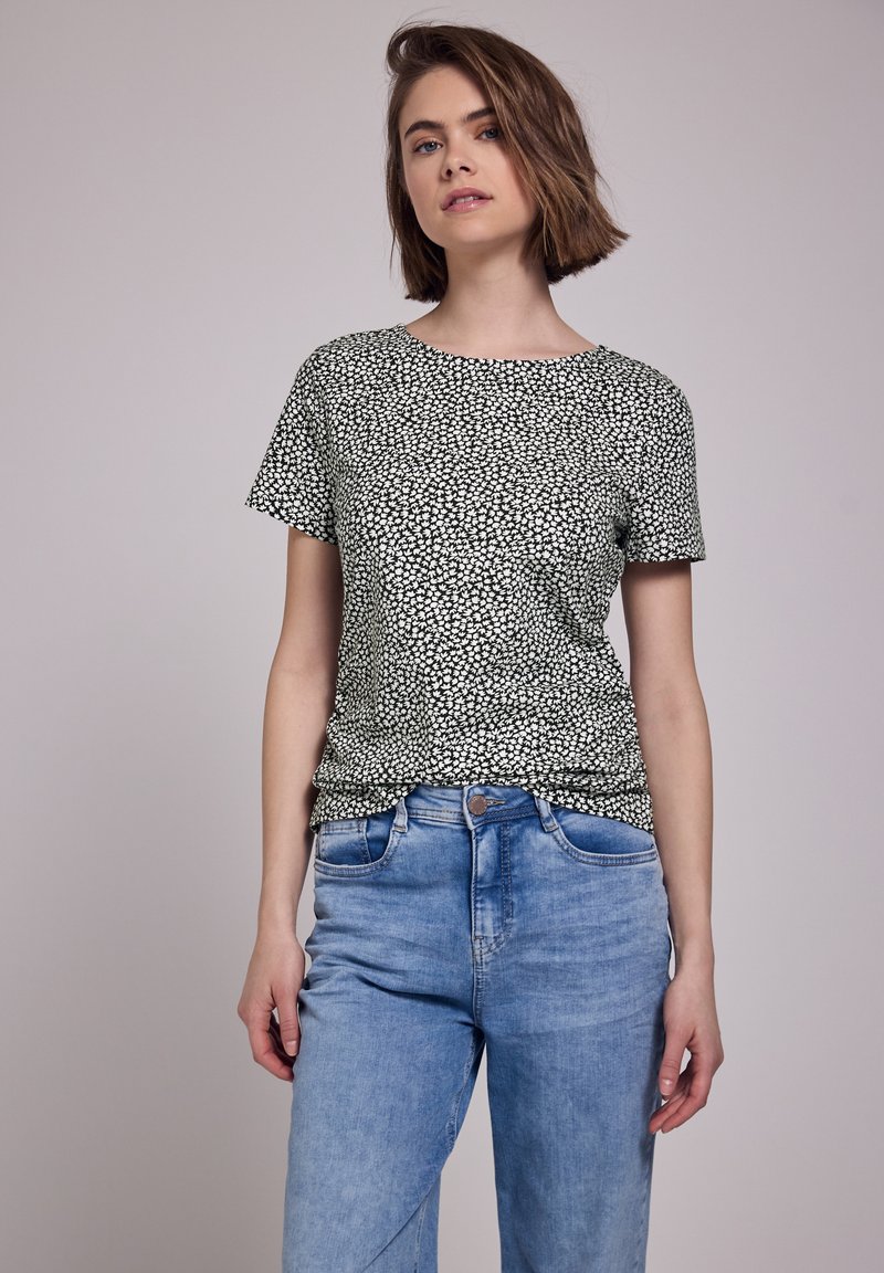 Top a maniche corte, con scollatura rotonda, in stampa floreale bianca e nera, abbinato a jeans a vita alta blu chiaro; materiale in misto cotone, vestibilità casual.