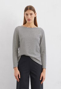 Long-sleeved, navy and white striped top in a soft, lightweight fabric with a bateau neckline and relaxed fit, paired with black pants.