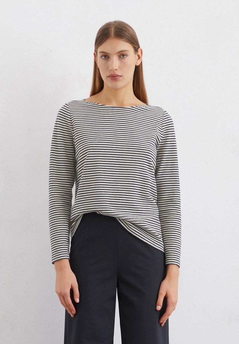 Long-sleeved, navy and white striped top in a soft, lightweight fabric with a bateau neckline and relaxed fit, paired with black pants.