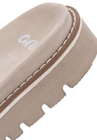 Sandale à plateforme en daim beige avec des détails de couture le long de la semelle et une semelle extérieure en caoutchouc épaisse, rainurée et crantée.