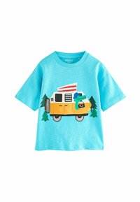 Lyseblå t-shirt med korte ærmer, der har en broderet gul campingvogn, grønne træer og et tegneserieagtigt krybdyr med et kamera.