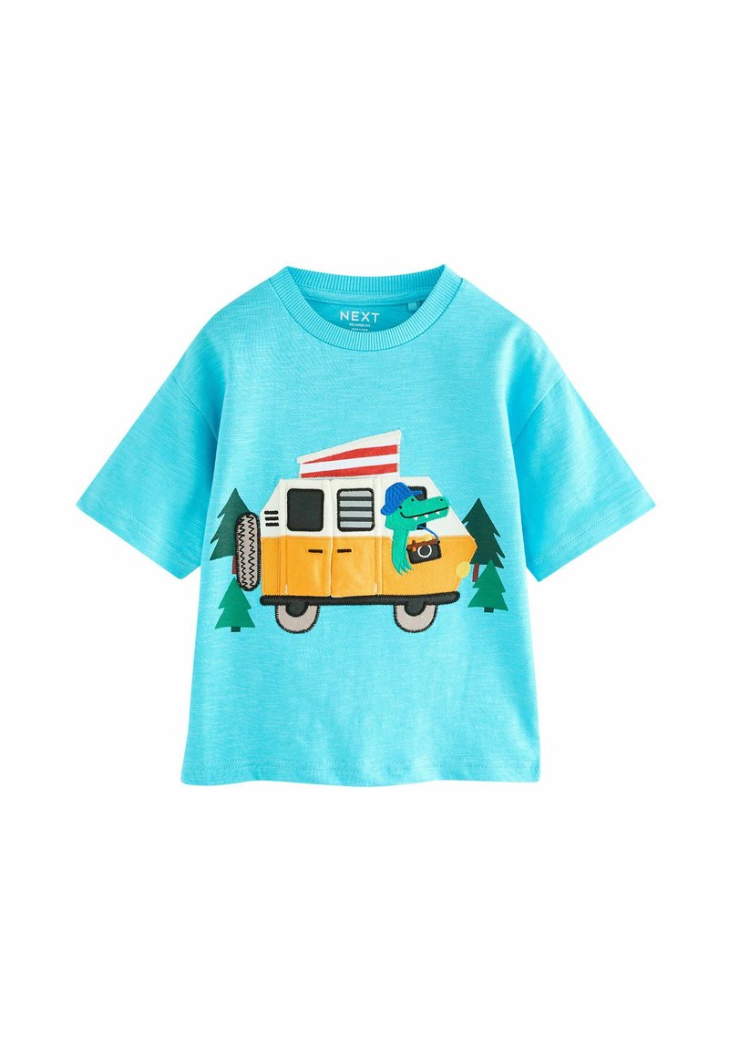 Lyseblå t-shirt med korte ærmer, der har en broderet gul campingvogn, grønne træer og et tegneserieagtigt krybdyr med et kamera.