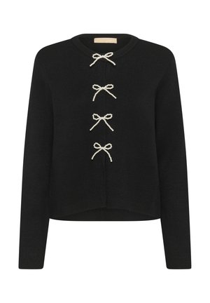 Maglione nero lavorato a maglia con maniche lunghe, scollatura rotonda e tre fiocchi bianchi decorativi. Orlo dritto con una vestibilità leggermente accorciata.