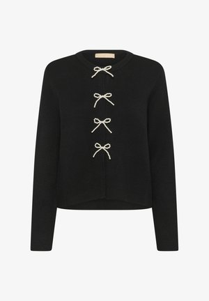 Maglione nero lavorato a maglia con maniche lunghe, scollatura rotonda e tre fiocchi bianchi decorativi. Orlo dritto con una vestibilità leggermente accorciata.