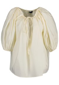 Blouse jaune pâle à coupe ample, manches bouffantes, poignets élastiques et encolure froncée avec un lien ajustable. Tissu en coton doux.