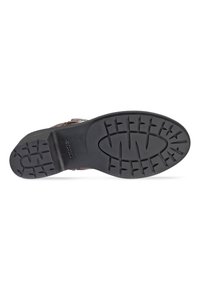 Suela de goma negra de un zapato con un patrón de agarre texturizado, forma ligeramente curvada y detalle de marca en relieve cerca del talón.