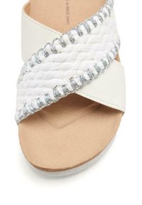 Sandal bianco con cinturino intrecciato e dettagli in argento, sole beige morbido e design a bande incrociate; dettaglio intrecciato testurizzato.