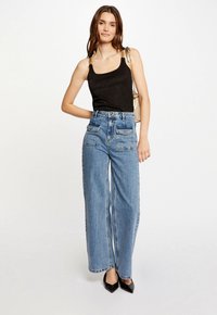 Black metallic camisole top, high-waisted light blue denim wide-leg jeans, and black pointed-toe heels. Includes a gold strap handbag.