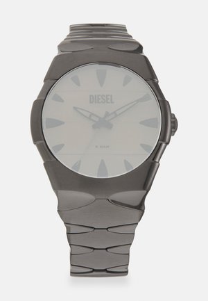 Montre noire en métal avec un cadran rond, de grands index et un design de bracelet lisse. Caractérisée par un style minimaliste et une résistance à l'eau de 5 bars.