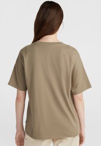 Bruine katoenen t-shirt met korte mouwen, ronde halslijn en een losse pasvorm. De stof lijkt glad en lichtgewicht zonder zichtbare patronen.