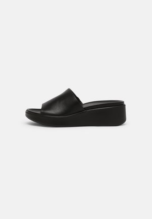 Sandales à glisser en cuir noir avec un bout ouvert arrondi et une semelle compensée. Le design est minimaliste et lisse, avec une finition légèrement brillante.