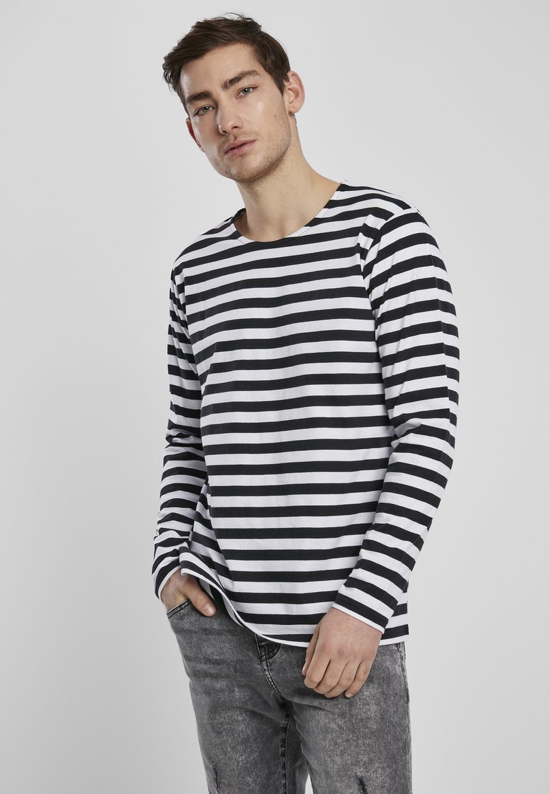 Een zwarte en witte gestreepte blouse met lange mouwen van katoen, met een ronde halslijn en een ontspannen pasvorm. Gecombineerd met grijze spijkerbroeken.