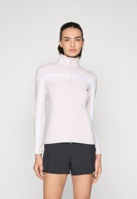 Lyserød zip-up jakke med høj krave og hvide striber. Blødt materiale, tætsiddende design, parret med sorte shorts. Brændlogo synligt.