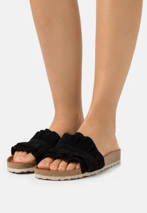 Des sandales noires à enfiler avec des brides en tissu froncé, une semelle en liège et en caoutchouc, présentant un design texturé et une coupe large pour le confort.