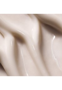 Material cremoso y de textura suave en beige claro, con ondas fluidas y un acabado brillante con reflejos sutiles.