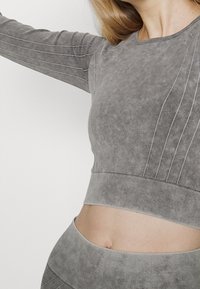 Grau geschnittenes Sweatshirt aus strukturiertem Stoff mit geripptem Saum, langen Ärmeln und dezenten gestickten Details an den Ärmeln.
