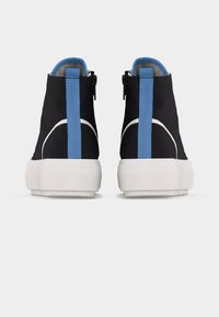 Para czarnych tenisówek za kostkę z grubymi białymi podeszwami i niebieskimi pętelkami na pięcie, widoczna od tyłu na białym tle.