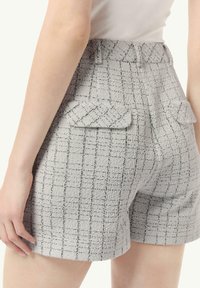Graue gewebte Shorts mit einem karierten Muster, ausgestattet mit zwei Gesäßtaschen und einem taillierten Bund. Der Stoff hat ein strukturiertes Aussehen.