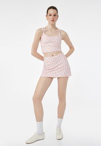To-delt outfit bestående af en lyserød top og mini nederdel med et lille blomstermønster. Fremstillet af letvægtsstof, justerbare stropper.