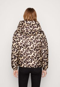 Chaqueta tipo plumón con estampado de leopardo, que presenta capucha, cierre con cremallera y puños elásticos. El material parece brillante y tiene una textura acolchada.