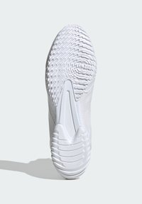 Suela de zapatilla deportiva blanca con patrones de tracción, acabado texturizado y sección del talón suave. El diseño general es aerodinámico y minimalista.