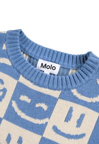 Blauer und cremiger, gestrickter Pullover mit Smiley-Gesicht-Muster, gerippter Halslinie und sichtbar etiketiertem "Molo" am Kragen. Weicher Textilstoff.