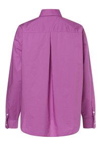 Pitkähihainen paita kirkkaan pinkissä yhtenäisessä kankaassa, jossa on selkämyksessä laskos, napilliset kalvosimet ja klassinen kaulus. Kangas on sileä ja hieman teksturoitu.