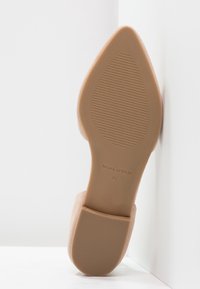 Scarpa con tacco alto beige, con punta affusolata e suola testurizzata caratterizzata da scanalature orizzontali. Nome del marchio "Marc O'Polo" visibile sulla suola.