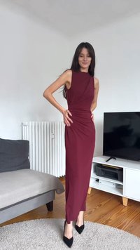 Vingröd ärmlös klänning med draperad halsringning och figursydd siluett. Golvlång design med slät textur och detaljer med rynkning på sidan.