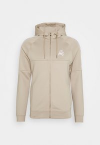 Beige zip-up hoodie i mjukt material, med huva, snörning och vita sidoflikar. Framläggs logotyp och två sidofickor.