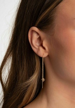 Guldhängande örhängen har en tunn kedja och stjärnformade detaljer. Designen är minimalistisk med en delikat textur och lyster.